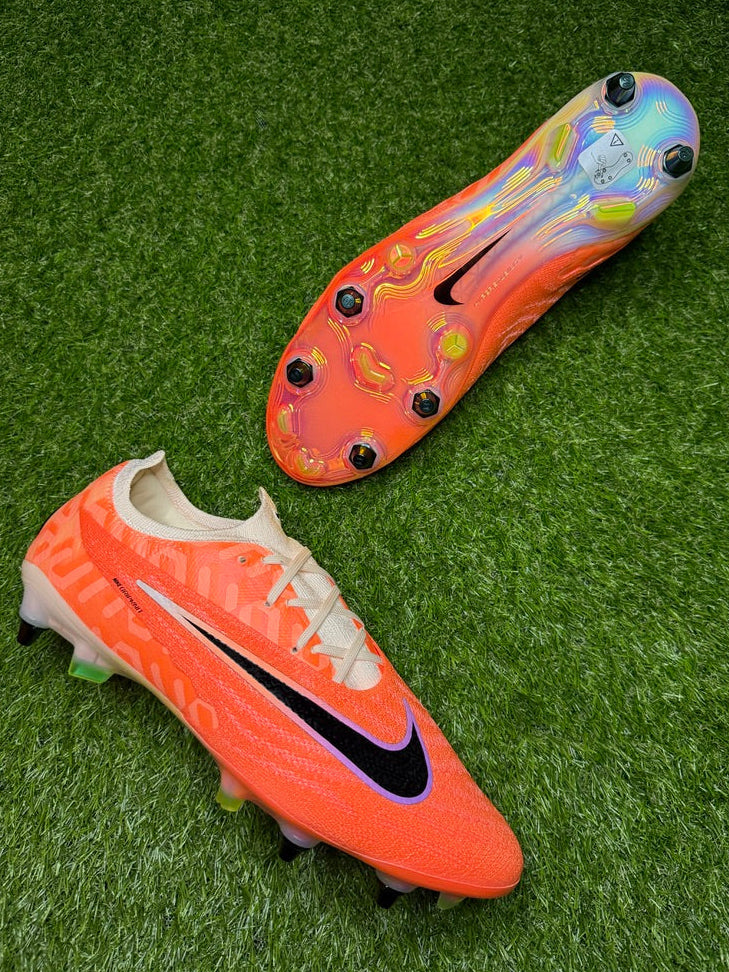 Two orange soccer cleats with black Nike logo on a green grass background